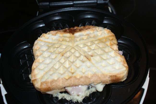 Toas med skinka och ost i våffeljärn. Toast with ham and cheese in a waffle iron. Vohveliraudalla paahdettu kinkku- ja juustoleipä. 